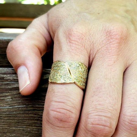 womans hand wearing a green diamond and yellow gold ring