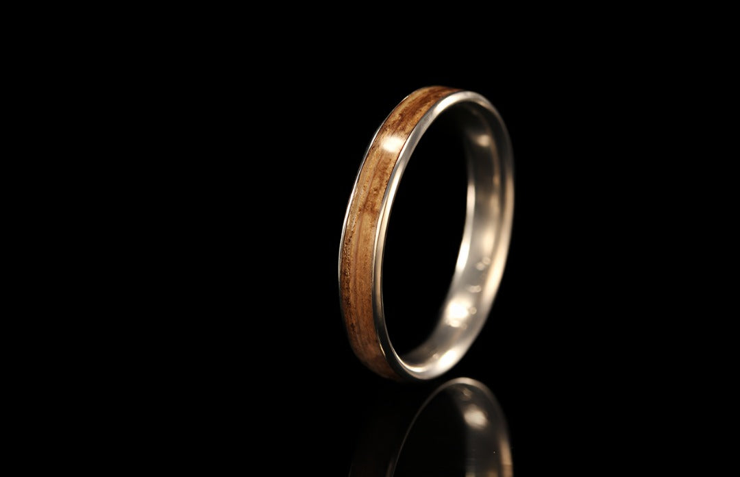 titanium ring with black background, upright view, golden interior band with a wooden exterior band, Chasing Victory