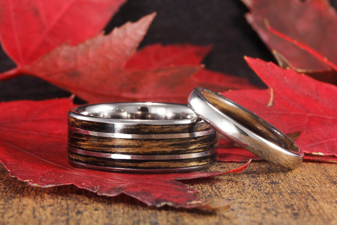 Fall Setting of men's ring with women's wedding ring leaning on men's ring. fall leaves