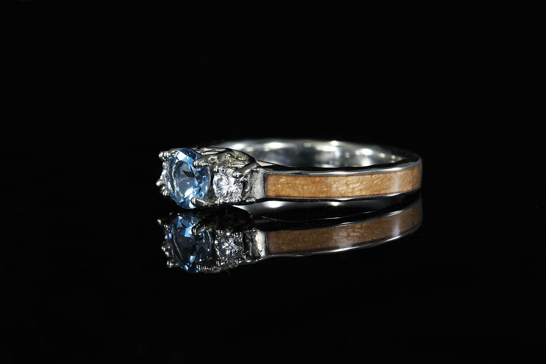 3 stone "Coral of the Sea" engagement ring, side view, wooden band with silver lining
